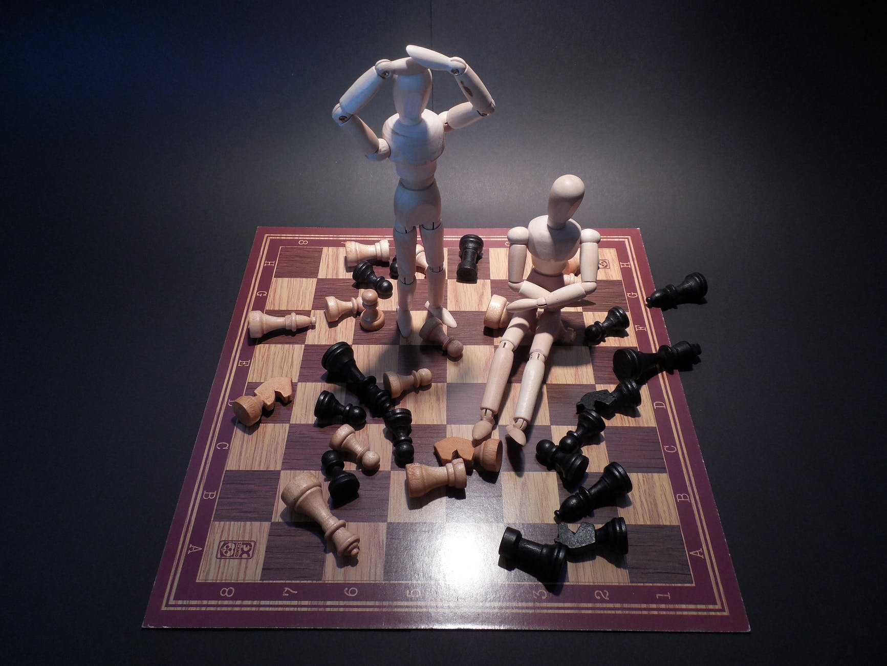 Two white wooden mannequins on a chess board