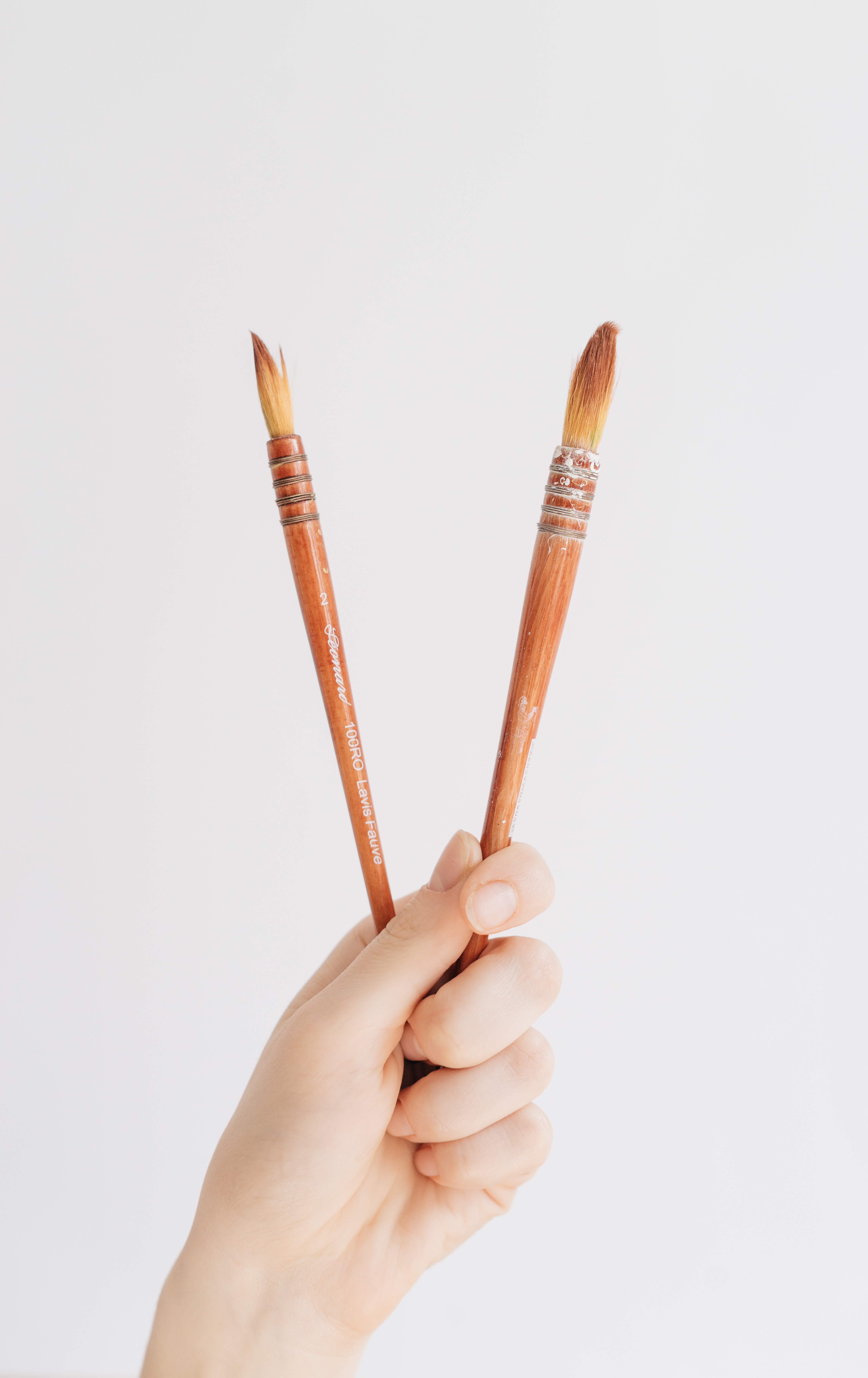 Two paintbrushes being held
