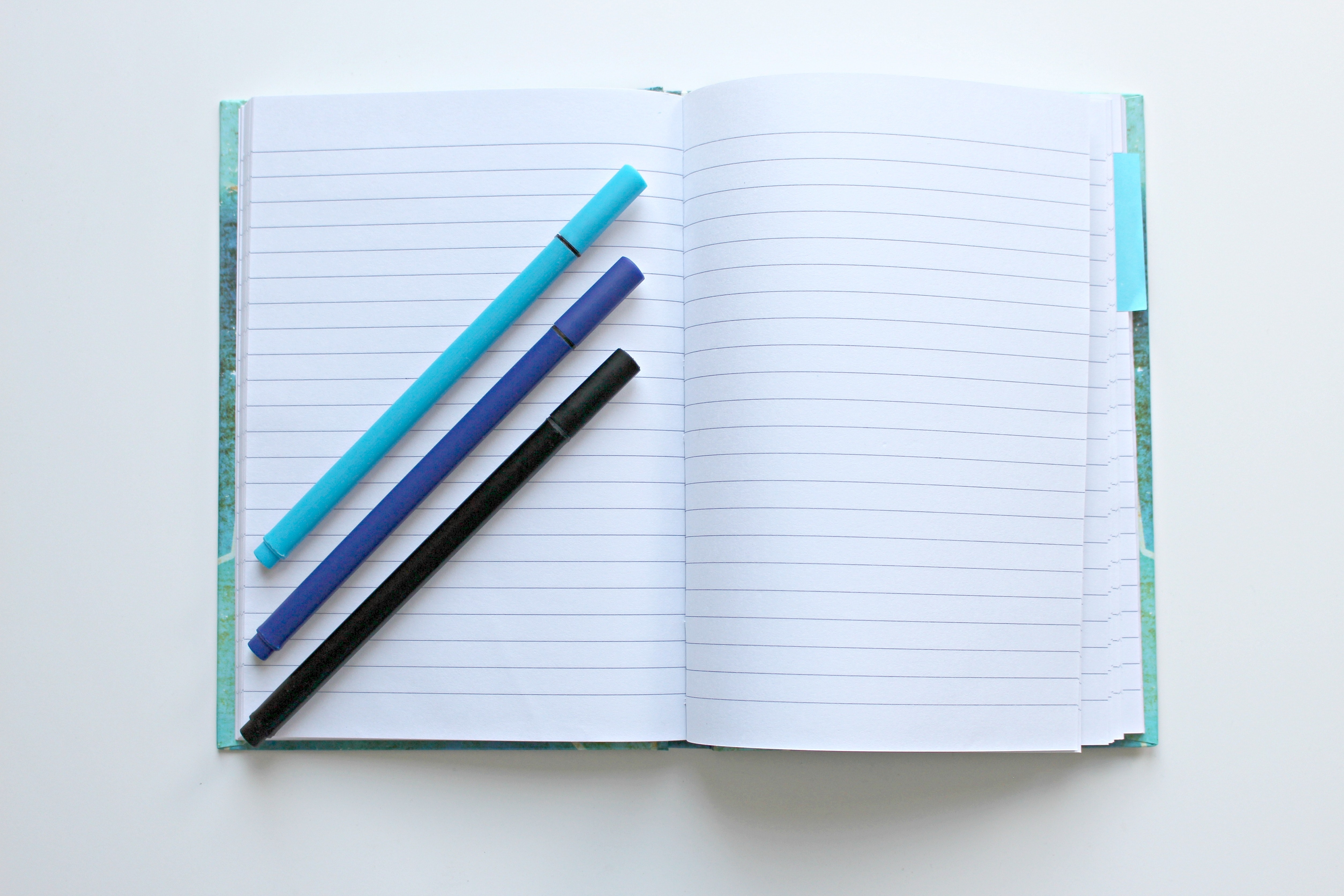 Three pens on a blank notebook