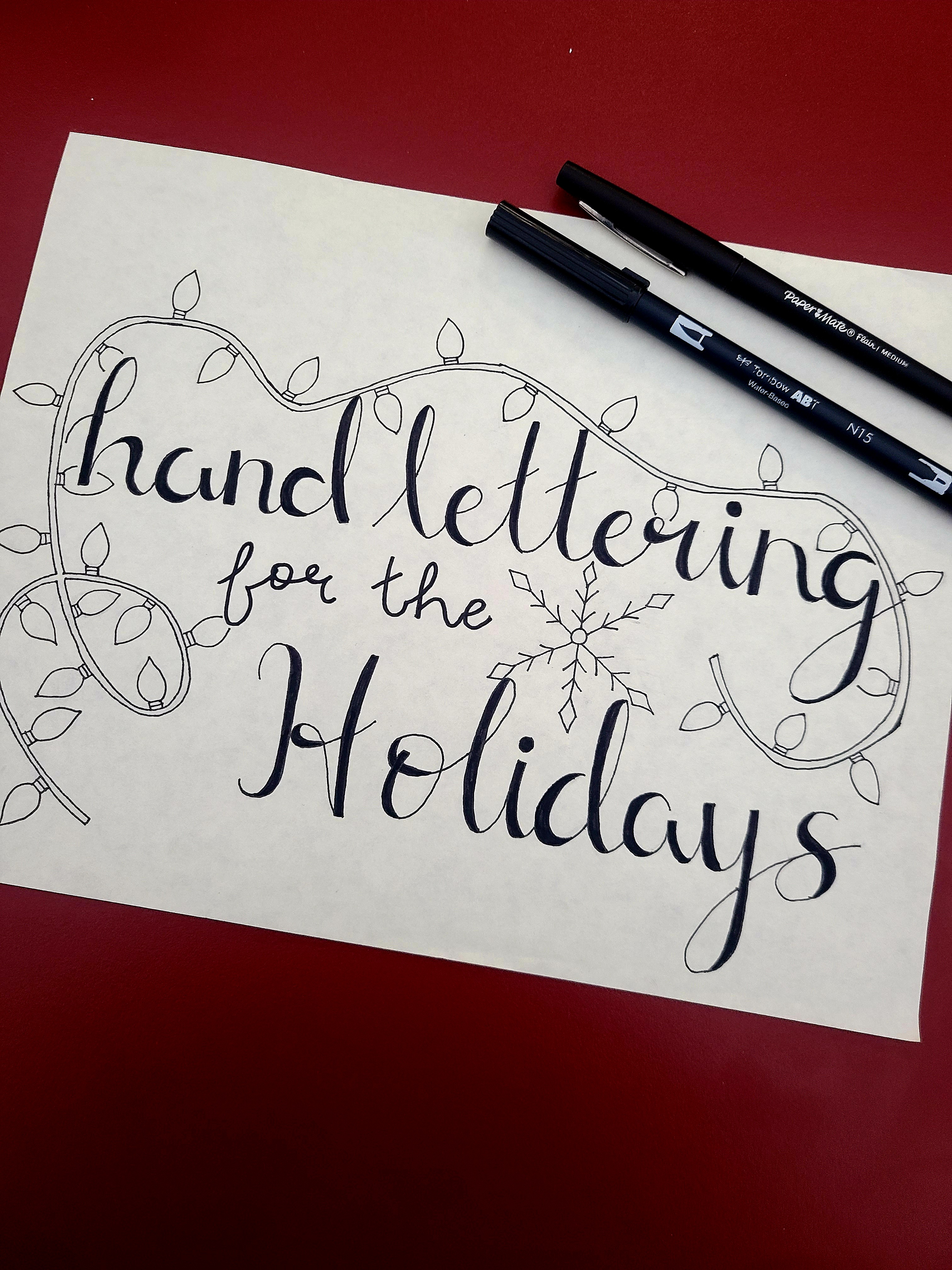 paper with script saying hand lettering for the holidays 