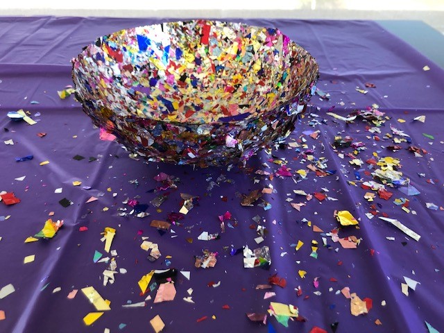 example of finished craft - a bowl made of confetti pieces.  Pictured on a purple table cloth.