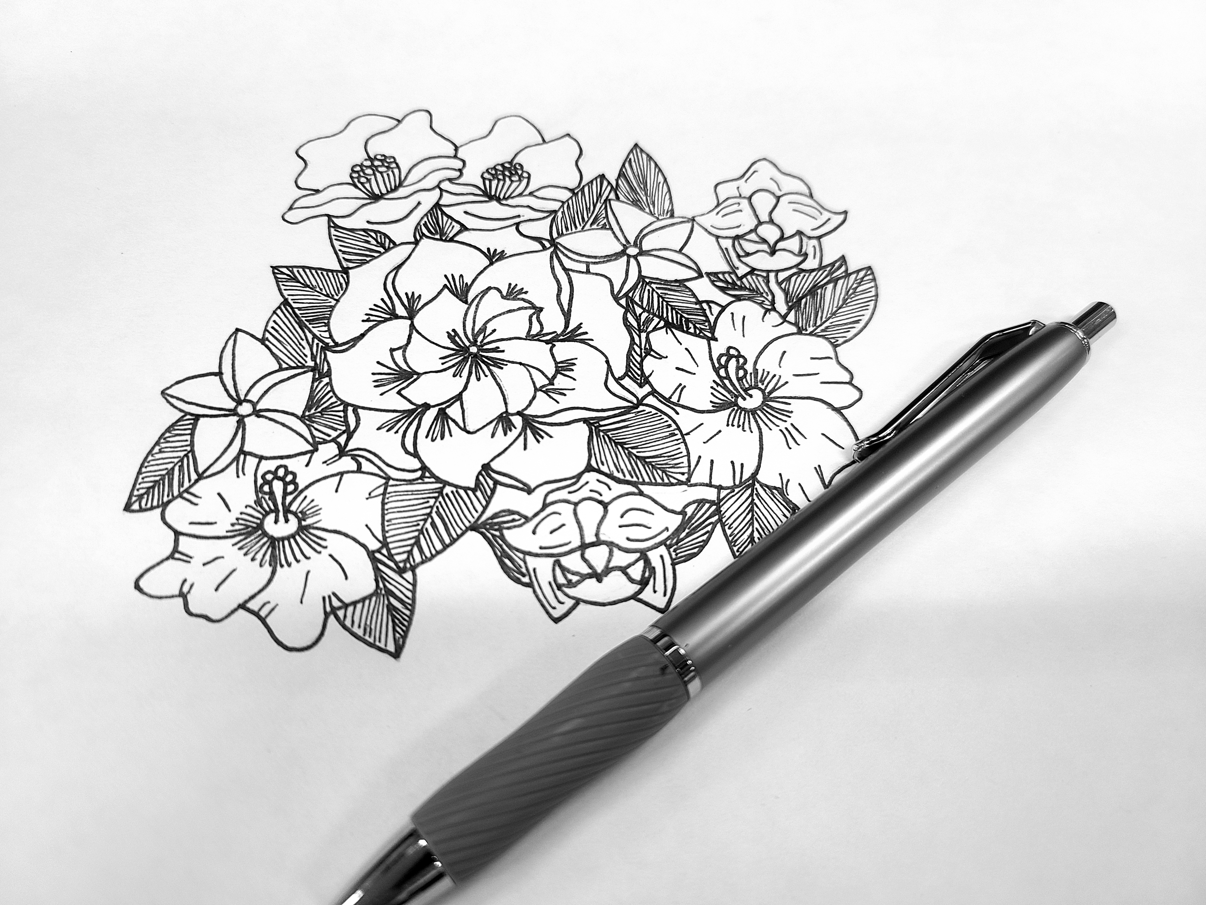 A black and white drawn flower next to a pen