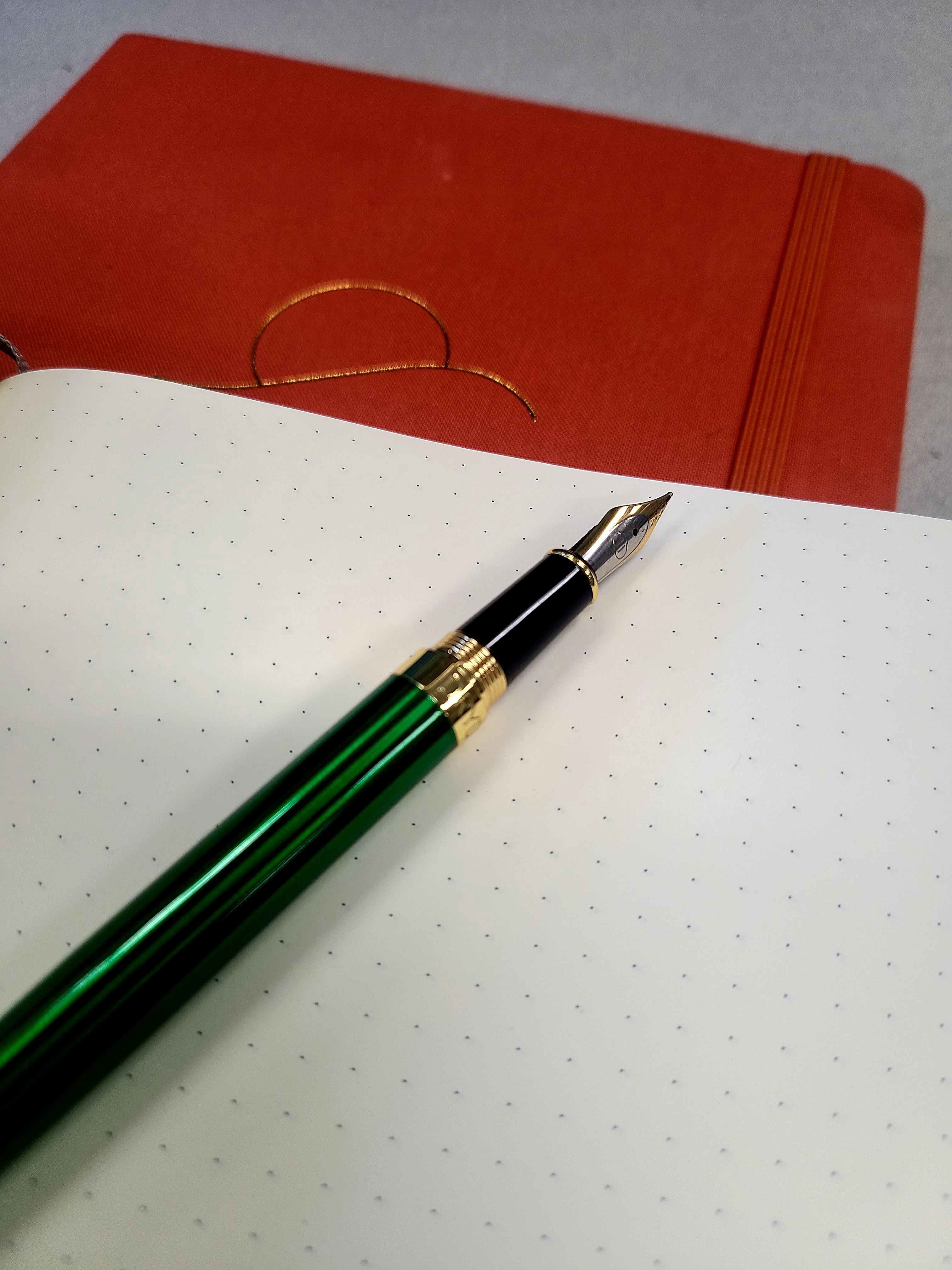 A red journal, grid paper, and a pen