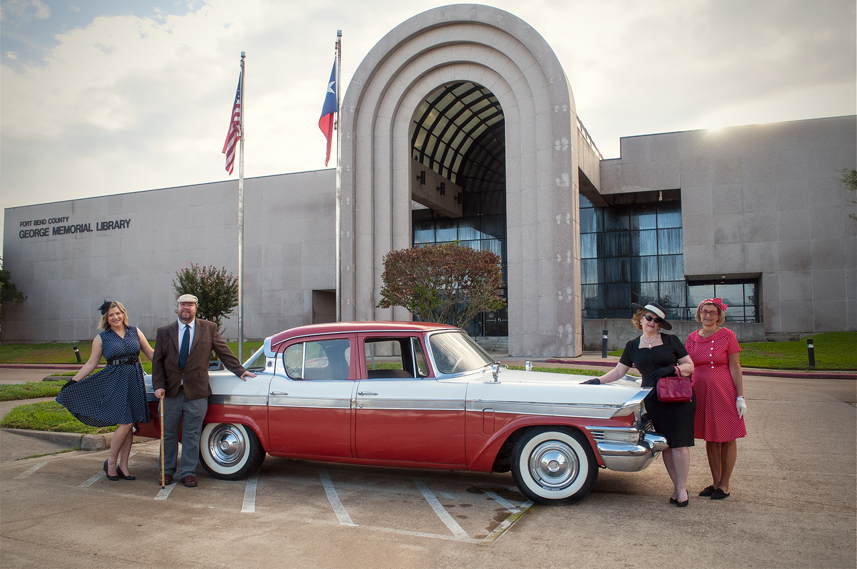 Vintage car in front of George Memorial Library with Library staff dressed in 1940s attire standing around the car. 