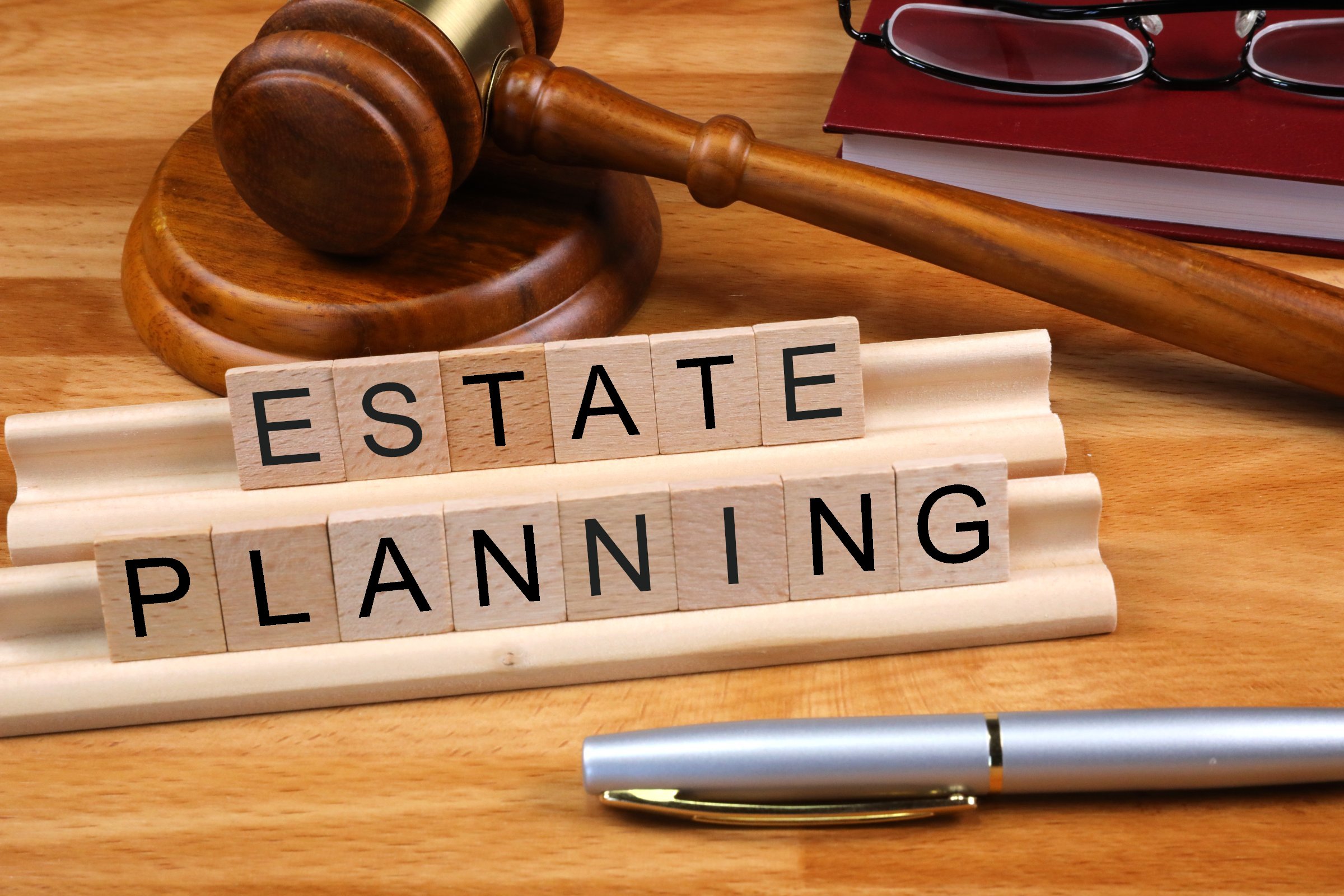 Pen and gavel next to a sign reading "Estate Planning" (Photo credit to Nick Youngson)