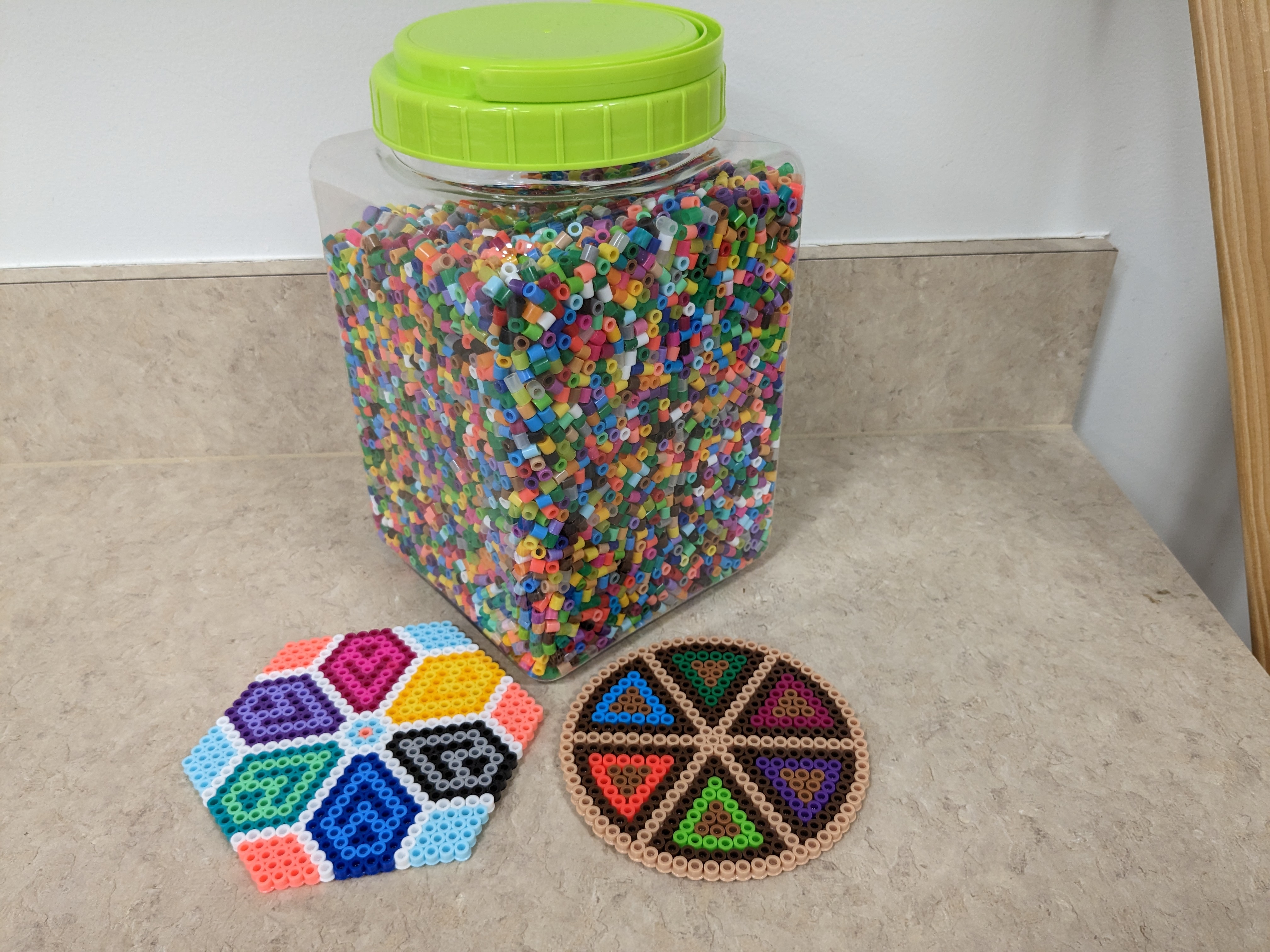 containter of beads and two coasters made from perler beads