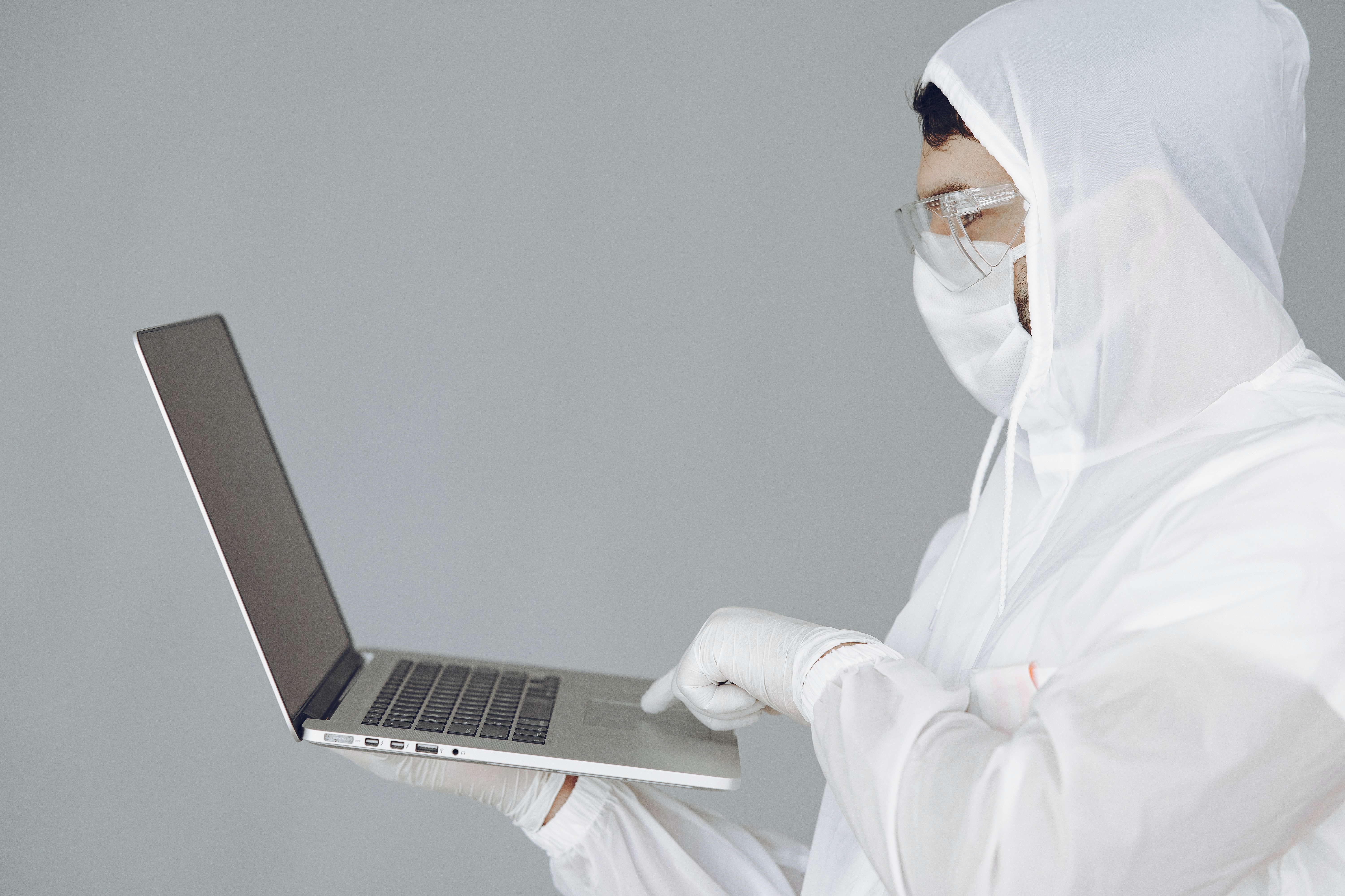 Person in a hazmat suit looking at a laptop