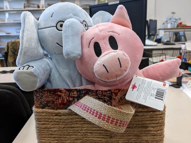 Two stuffed animals in a caddy lined with fabric and wrapped with twine.