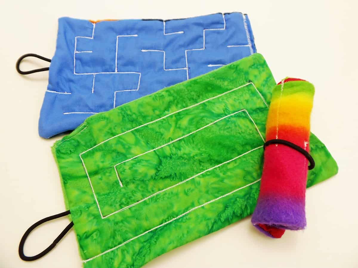 Two fidget mazes made of cloth with sewn maze paths.
