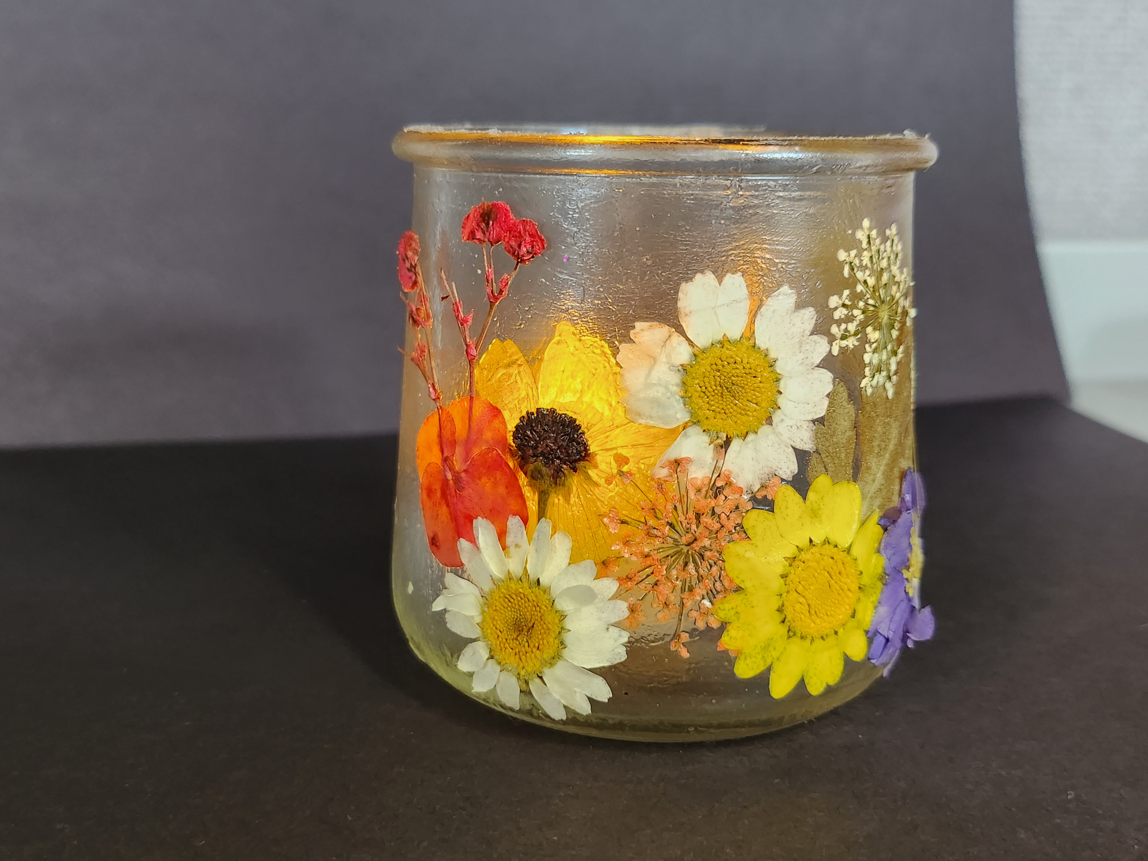 Glass jar with pressed flowers on the sides of the jar