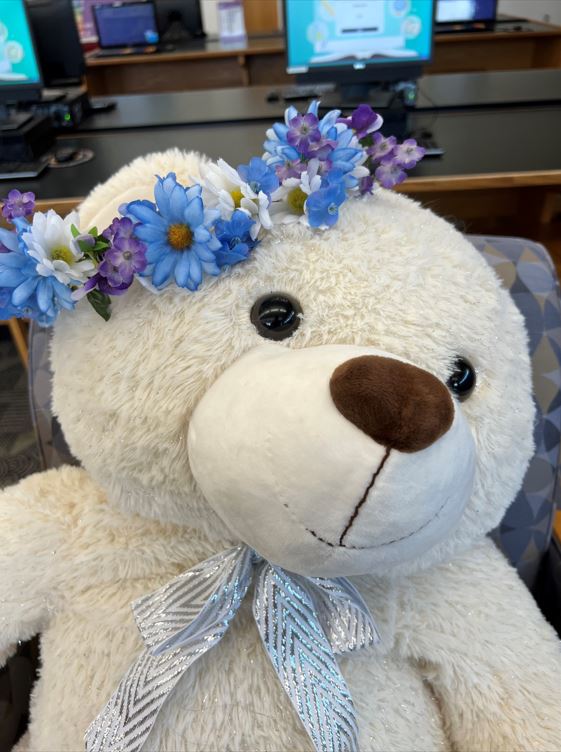 A stuffed bear with a flower crown on its head