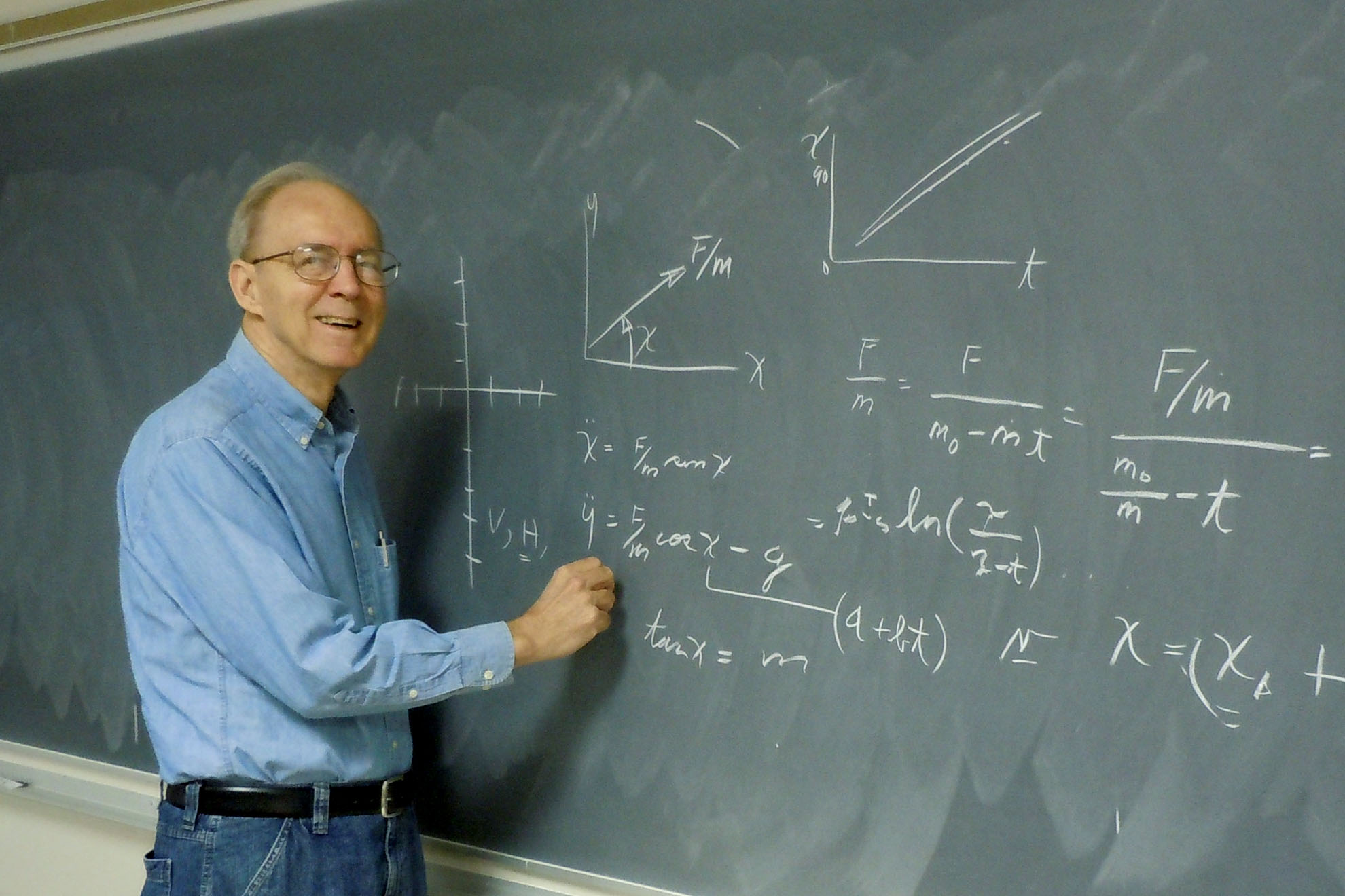 Program presenter, F Don Cooper, at a chalkboard with equations written on it.