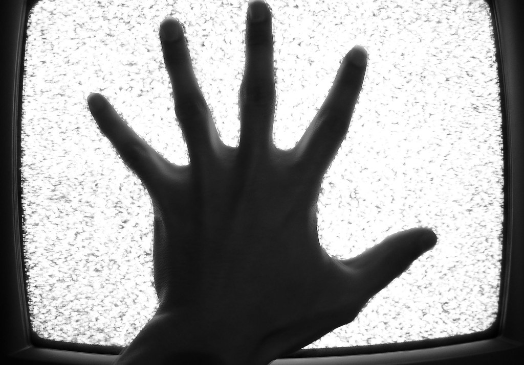 silhouette of hand on tv with static