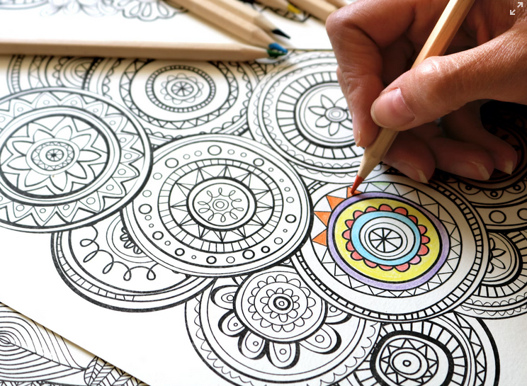 close up of someone coloring with colored pencils on an abstract coloring sheet