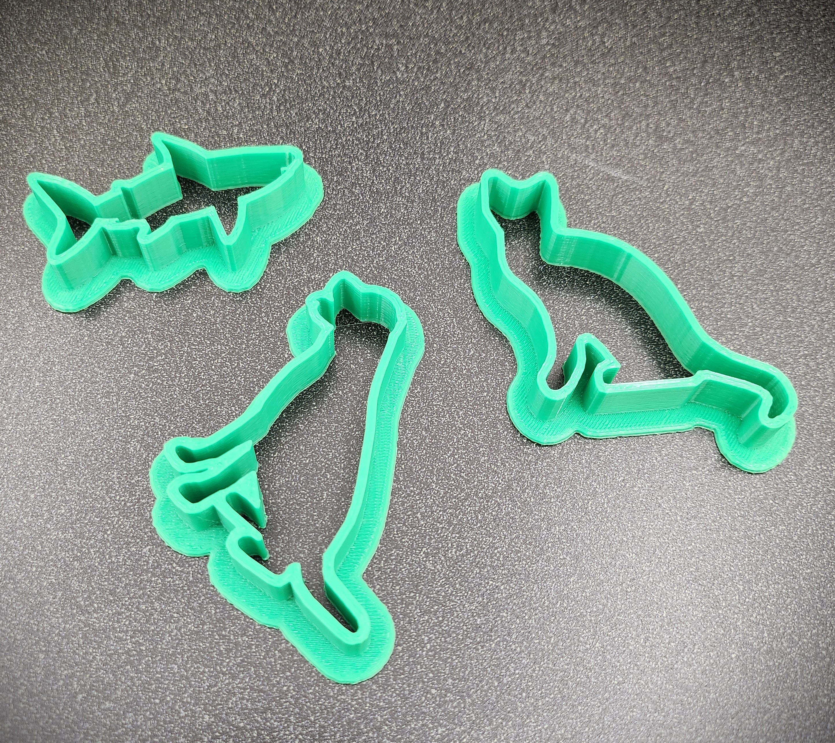 photo of bright green 3D printed cookie cutters in the shape of a shark, dog, and cat