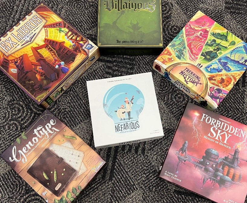 photo of five board game boxes on a floor surrounding a sixth board game box