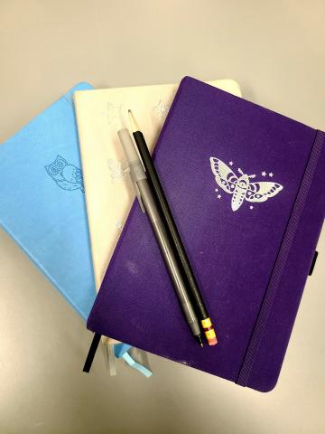 Three journals along with a pen and pencil