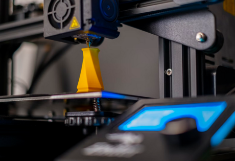 photo of a 3D printer printing an orange abstract piece