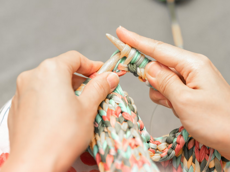 close up of hands knitting with large bamboo needles