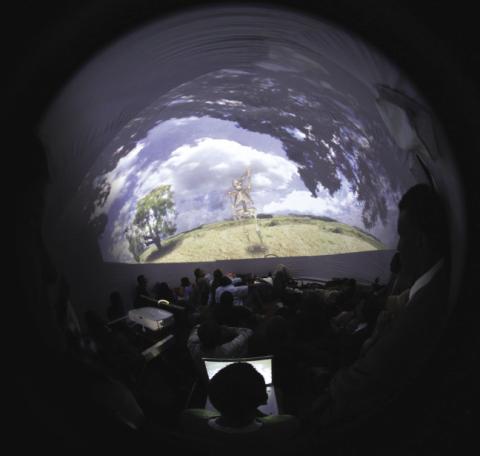 People watching a film being projected on the inside of a dome.