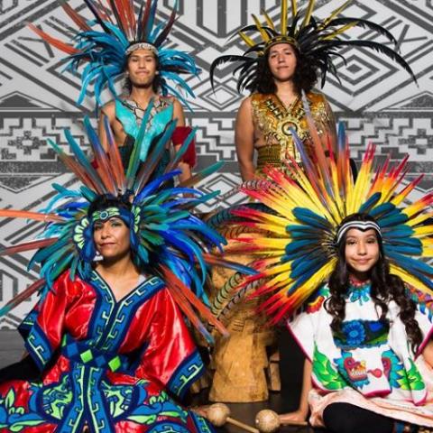 Performers from Houston Aztec Dance & Drum wear colorful costumes with feather headresses.