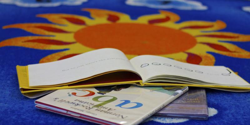 Children's books spread on colorful carpet