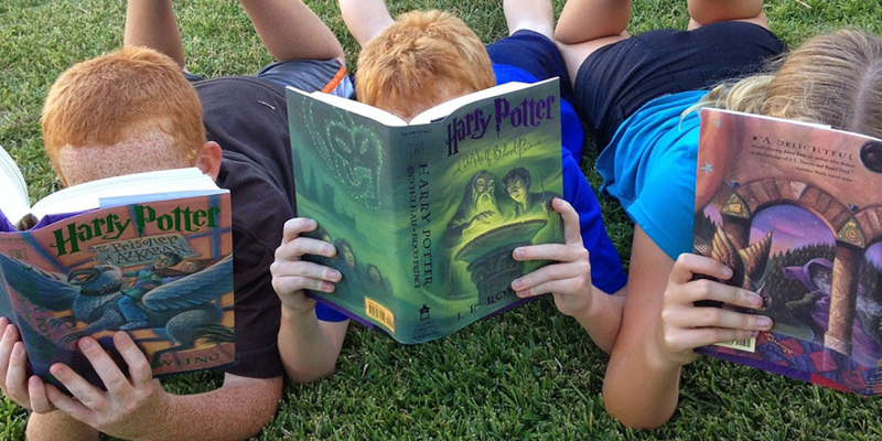 Three children reading Harry Potter books