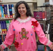 Woman wearing a pink sweatshirt with a gingerbread man on the front