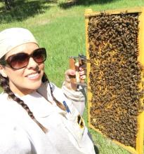 Danessa "Nes" Yaschuk stands in front of a bee hive